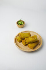 Risoles, a snack from Indonesia served with a little green chili in a wooden plate. Risol and green...