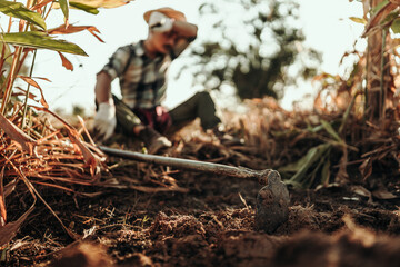 Gardeners use a hoe to dig up the soil to prepare the area for planting vegetables.