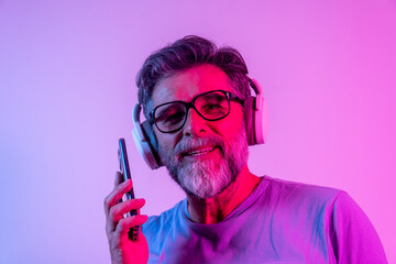 Mature handsome model posing in a studio in a trendy neon light. Fashionable man with headphones. Vibrant color. Bright colorful light effects. Disco style. Overlay. Gel filter. Supersaturated