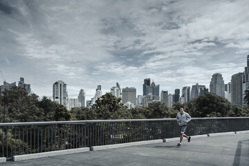 A man running up on footbridge in the city center park for cardio workout.  Health and Lifestyle in big city life concept.