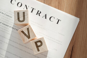 Wooden cubes makes word UVP - abbreviation Unique Value Proposition on contract background.