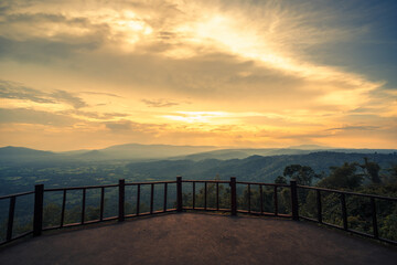 Obraz premium The wooden balcony has a view of the mountains and sunset behind.