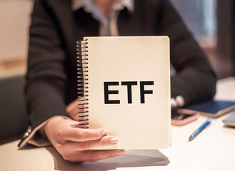 A woman hand holding a notebook with the word ETF