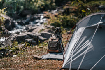 tents pitched on hillsides beside streams of water from waterfalls. hiking bag, hiking shoes on the ground.