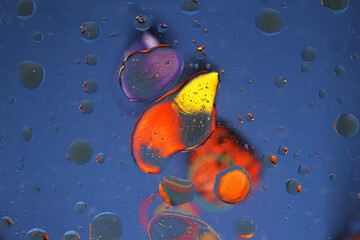 An image of multicolored droplets on glass on a blue background.