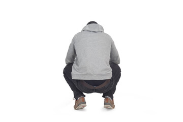 back view of man squatting and looking down on white background