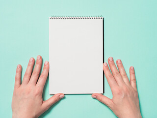 Blank paper notebook and female hands