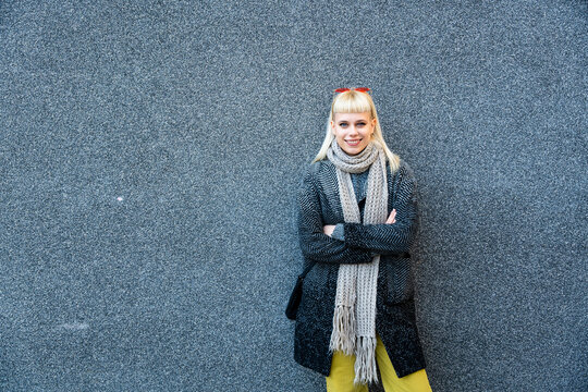 Portrait of young confident fashionable woman with cool attitude. Hipster stylish female posing against black wall.