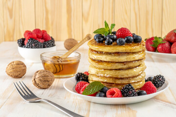 Delicious pancakes with fresh berries on white wooden table. Food concept.