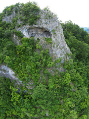 Viewpoint above mountains of a cave, eroded in a calcareous cliff on a steep mountain side. The tunnel has its stone walls covered with moss. The arches in the cave are untied by a pillar. Carpathia