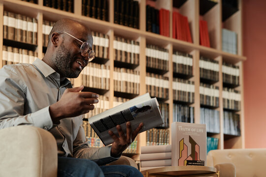 Confident author of book looking at page with text and explaining it to public during presentation at literature event