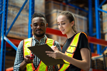 Two people in safety vests looking at a clipboard. One is a man and the other is a woman