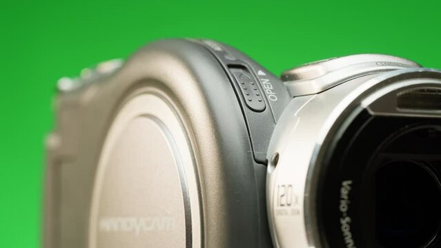 Vintage video-camera with disk inside rotating on green background close-up. Using portable camcorder to shooting videos