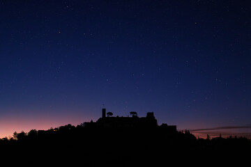 Star filled night sky over the silhouetted medieval village of Turenne in the Correze department of...