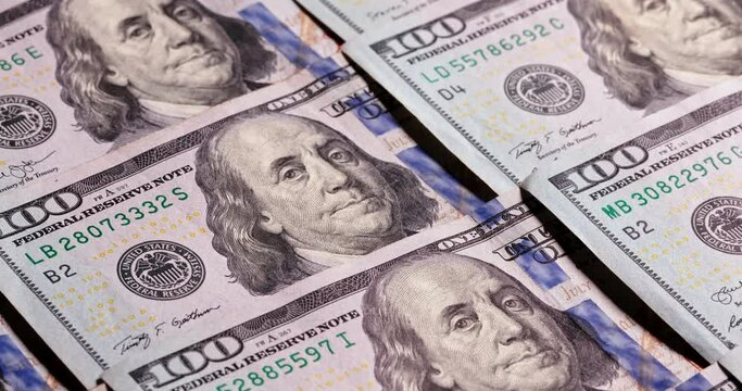 New crisp one hundred dollar bills are located on surface. Benjamin Franklin looks out from neat rows of laid out banktons. Financing and profit in American dollars. Economic stability, copy space
