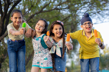 Group of kids having ice cream during summer camp .Kids having ice colorful ice candy enjoying...