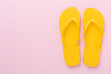 Bright yellow flip-flops on color background, top view. Summer concept