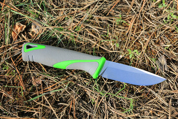 tourist survival knife against a background of pine needles in the forest - 785596432