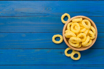 Corn ring crisps on wooden background, top view
