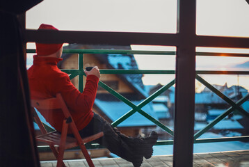 Man in winter clothing drinking hot herbal tea. Winter evening from a beautiful balcony in the...