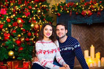 Obraz na płótnie Canvas Young couple near fireplace celebrating Christmas