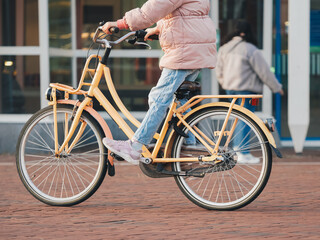 Fototapeta premium A young person is riding a yellow bike on a brick road