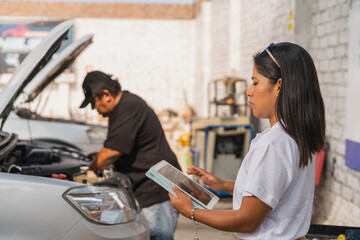 Woman using tablet next to mechanic in a repair garage