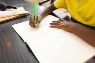 African American boy drawing in notebook, wearing a yellow shirt