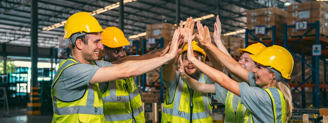 In a factory setting, a team of engineers and foremen emphasize safety and teamwork during a...