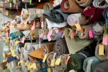 Storage of rolls of furniture fabric of different colors and textures on racks. A variety of...