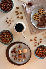 Cup of tea or coffee, cookies, macaroons, chocolate, various nuts and cocoa powder on white background. Top view.