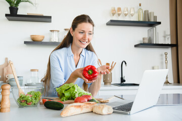 Young woman blogging on laptop online, talking about food blog at home kitchen. Vlogging concept. broadcasting on live. Veganism vegetarianism concept