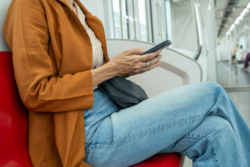 Close-up of a young woman's hand as she uses a smartphone while riding a train.