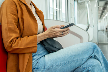 Close-up of a young woman's hand as she uses a smartphone while riding a train.