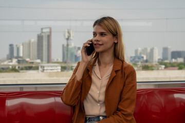 A young woman in casual attire is focused on her smartphone while riding on a modern subway train.