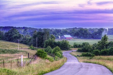 Valley Scene.  A winding country road meanders through a tranquil rural landscape, leading to a...