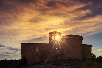 Sunset over the hermitage of San Frutos, Segovia, in the Hoces del Río Duraton with a sky of warm colors and the sun in the hole of the bell tower - obrazy, fototapety, plakaty