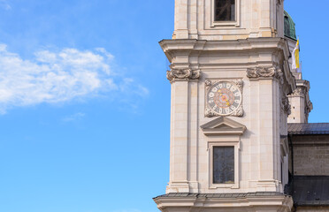 Part of the Salzburg Cathedral with a clock against a background of blue sky with cloud