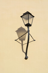 Salzburg street lamp on a wall with shadow during the day