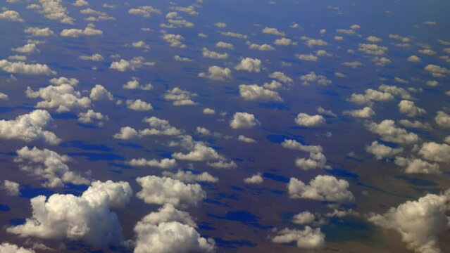 Scenic aerial view from airplane window featuring fluffy cumulus clouds and stunning landscape below. Ideal for travel and aviation concepts.