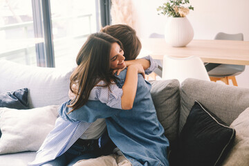 Beautiful young couple hugging in their new apartment. Engaged couples celebrate by hugging each other happily for their new home. Celebrating relationship achievement man and woman indoor leisure - obrazy, fototapety, plakaty