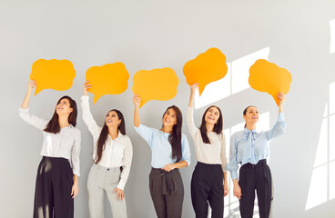 Happy girls, young female group of business people, friends holding empty paper speech bubbles,...