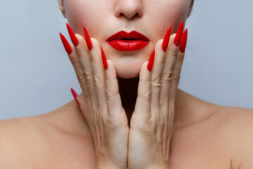 Closeup of Woman's Face with Red Stiletto Nails and Matching Lipstick