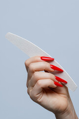Graceful Hand with Red Stiletto Nails Holding Nail File