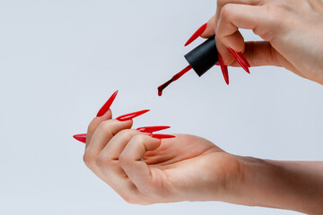 Application of Red Nail Polish on Stiletto Nails on Gray Background