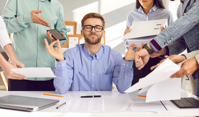 Calm young man in shirt and glasses sitting at working desk with eyes closed, mediating, relaxing,...