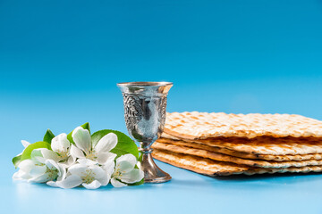 Happy passover. Metal goblet and traditional matzah on blue background.