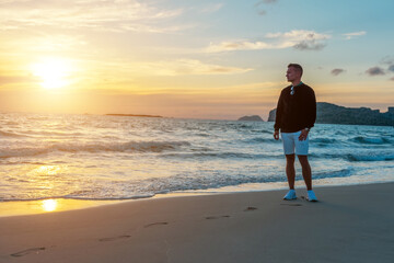 Man traveller on a tropical beach during sunset.