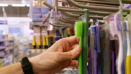 Close-up of a male hand taking a toothbrush in a supermarket
