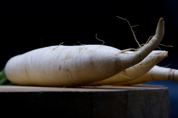 Radish root placed on wooden board. Dark and Still-life image. Close-up white radishes or Daikon...